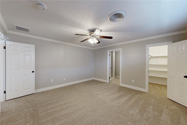 unfurnished bedroom with light colored carpet, a walk in closet, and visible vents