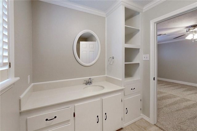 bathroom featuring built in shelves, ornamental molding, a ceiling fan, vanity, and baseboards