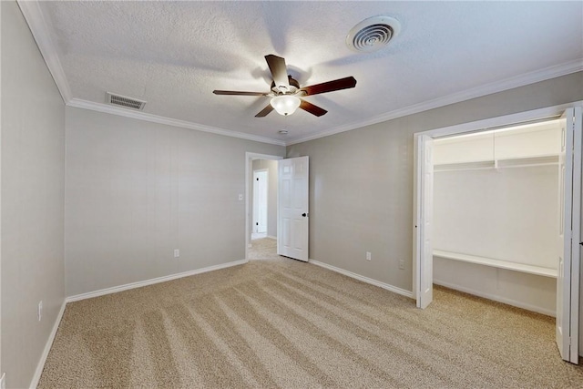 unfurnished bedroom with a textured ceiling, carpet floors, visible vents, and crown molding