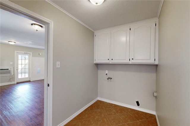 clothes washing area featuring cabinet space, baseboards, a wall unit AC, ornamental molding, and tile patterned floors