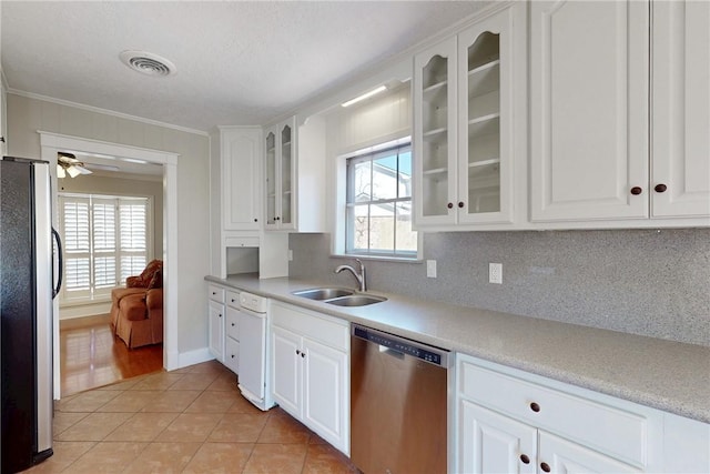 kitchen with crown molding, light tile patterned floors, stainless steel appliances, white cabinets, and a sink