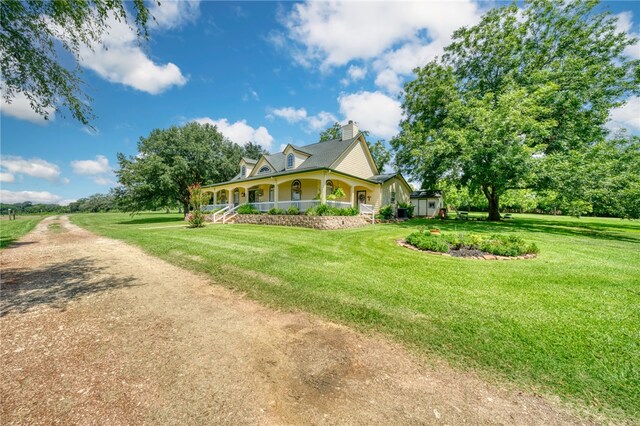 view of side of home with covered porch and a yard