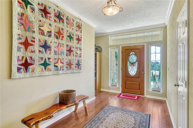 foyer with wood-type flooring, a textured ceiling, and ornamental molding