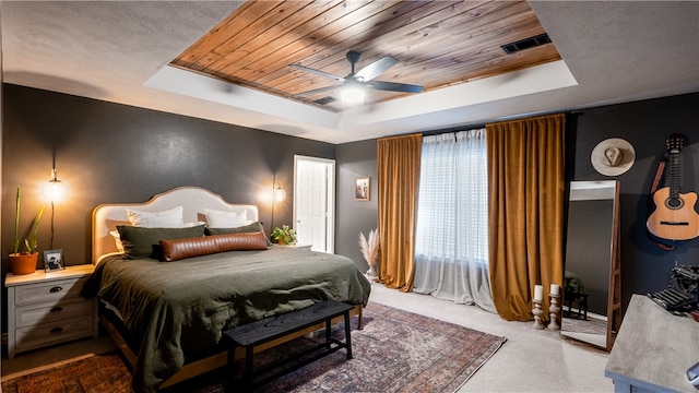 bedroom featuring a tray ceiling, wood ceiling, carpet, and visible vents