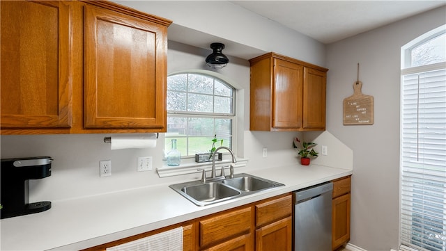 kitchen featuring a sink, brown cabinets, stainless steel dishwasher, and light countertops