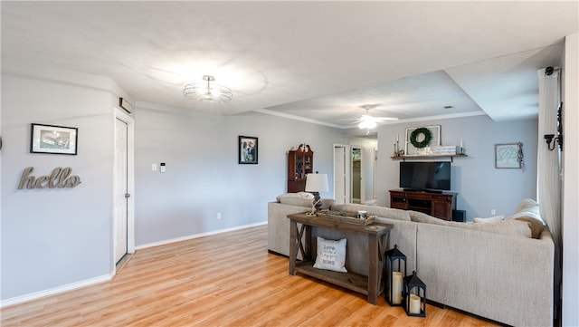 living area featuring ceiling fan with notable chandelier, crown molding, light wood-style floors, and baseboards