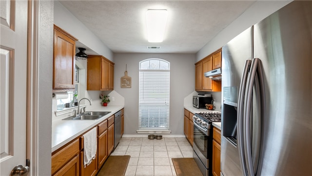 kitchen with visible vents, under cabinet range hood, light countertops, stainless steel appliances, and a sink