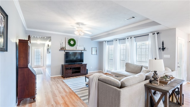 living area with visible vents, baseboards, wood finished floors, and crown molding