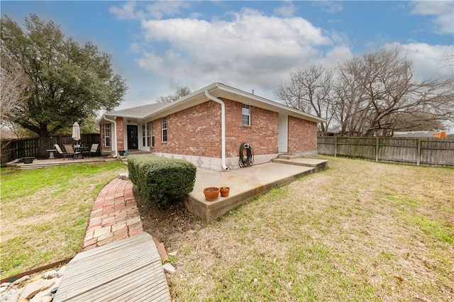 back of house with a patio, a yard, a fenced backyard, and brick siding