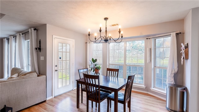 dining room featuring a chandelier, visible vents, light wood-style flooring, and baseboards