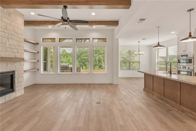 3568 Chantilly Path, Bryan, TX 77808 - unfurnished living room with ceiling fan, beamed ceiling, a stone fireplace, light wood finished floors, and a chandelier