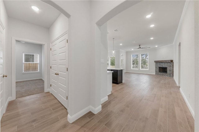 hallway with ornamental molding and light hardwood / wood-style flooring