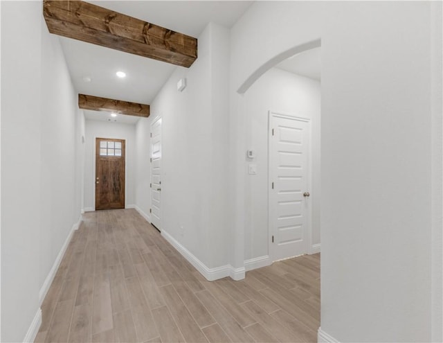 corridor with beam ceiling and light hardwood / wood-style flooring