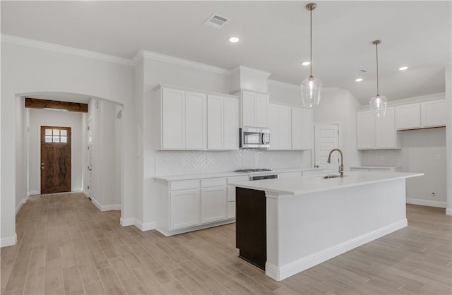 kitchen featuring pendant lighting, a kitchen island with sink, white cabinets, sink, and light hardwood / wood-style flooring