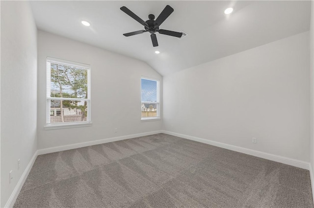 carpeted spare room featuring ceiling fan, lofted ceiling, and a wealth of natural light