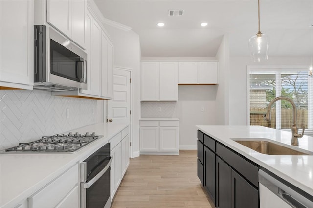 kitchen with sink, white cabinets, pendant lighting, and appliances with stainless steel finishes