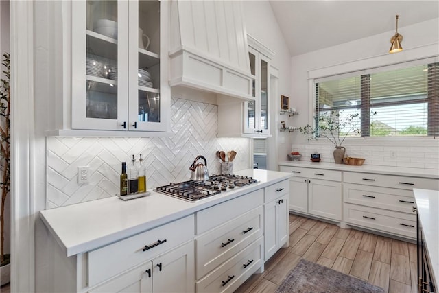 4209 Harding Ct, Bryan, TX 77802 - kitchen featuring decorative backsplash, light countertops, white cabinetry, vaulted ceiling, and custom range hood