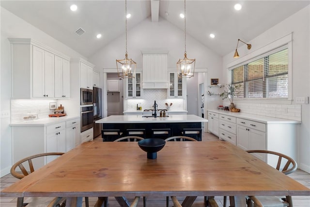 4209 Harding Ct, Bryan, TX 77802 - kitchen with stainless steel appliances, an island with sink, light countertops, high vaulted ceiling, and tasteful backsplash