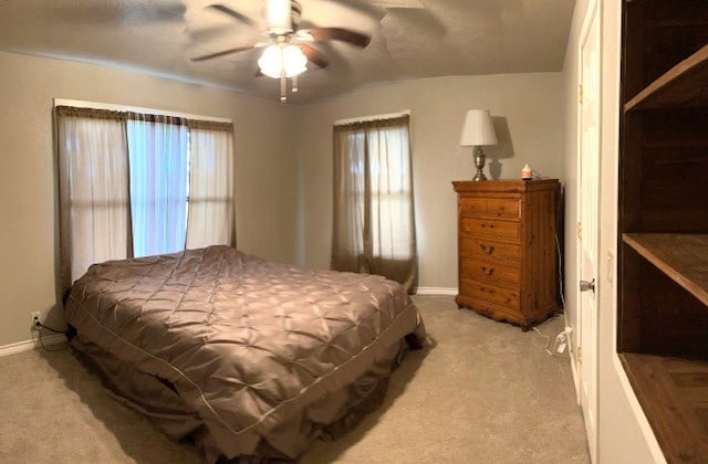 bedroom featuring baseboards, a ceiling fan, and light colored carpet