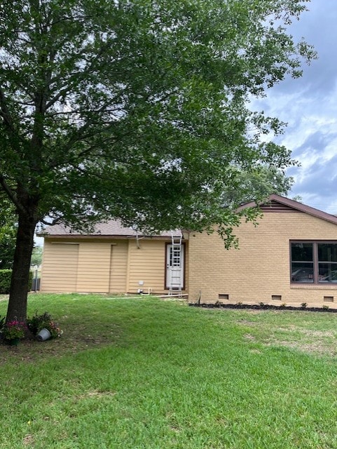 rear view of property featuring a lawn, brick siding, and crawl space
