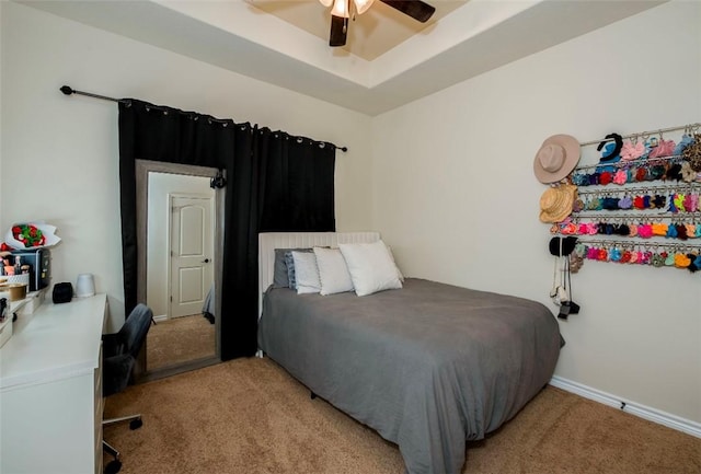 bedroom with light carpet, ceiling fan, a raised ceiling, and baseboards