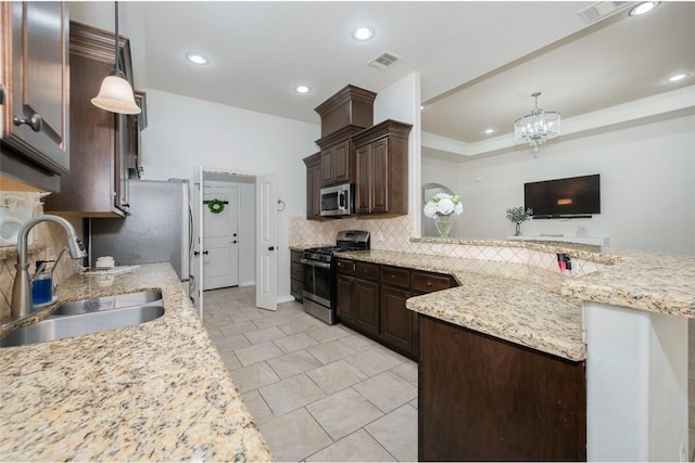 kitchen with appliances with stainless steel finishes, decorative light fixtures, a sink, and tasteful backsplash