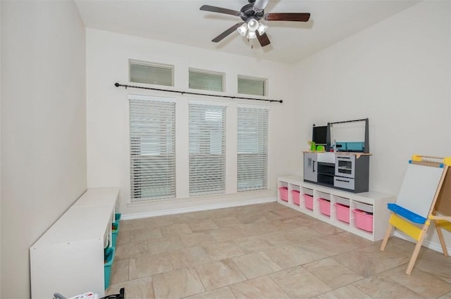 playroom with a ceiling fan and baseboards