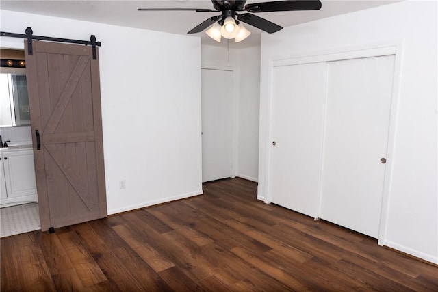 2323 Carter Creek Pkwy, Bryan, TX 77802 - unfurnished bedroom with dark wood-style flooring, a barn door, a closet, baseboards, and ceiling fan