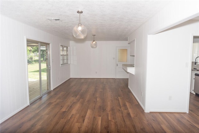 2323 Carter Creek Pkwy, Bryan, TX 77802 - unfurnished living room featuring dark wood-style flooring and a textured ceiling