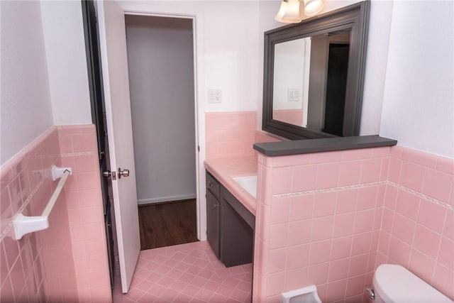 2323 Carter Creek Pkwy, Bryan, TX 77802 - half bath with vanity, toilet, tile walls, wainscoting, and wood finished floors