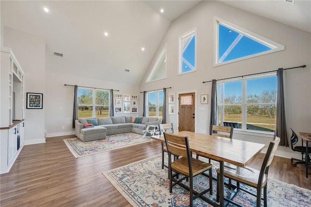 dining room with hardwood / wood-style floors and high vaulted ceiling