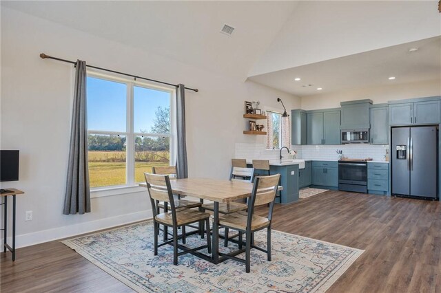 dining area with dark wood-type flooring and high vaulted ceiling