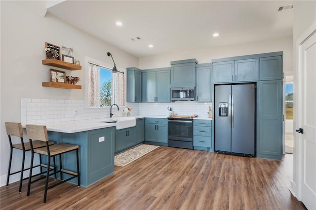 kitchen featuring a breakfast bar, dark wood-type flooring, sink, tasteful backsplash, and stainless steel appliances