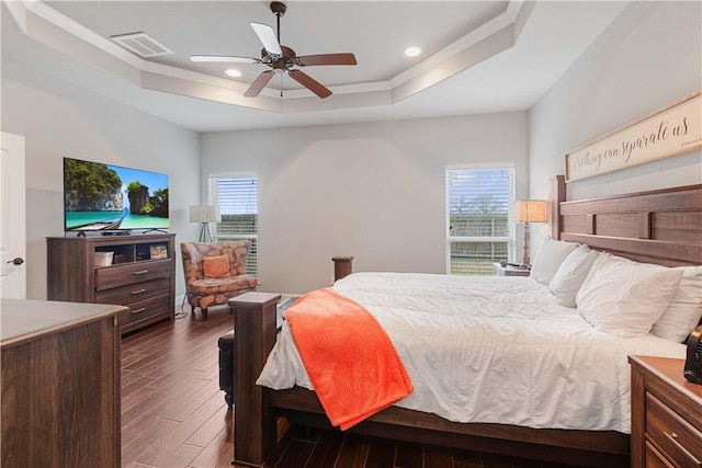 bedroom featuring dark wood-style floors, a raised ceiling, visible vents, and multiple windows