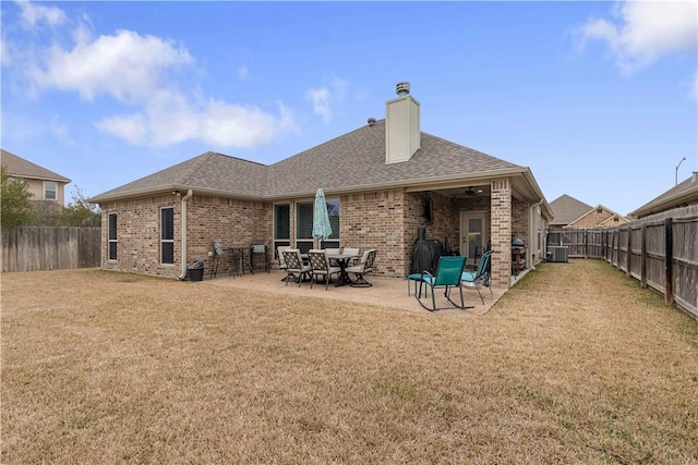 rear view of house featuring brick siding, roof with shingles, cooling unit, and a lawn