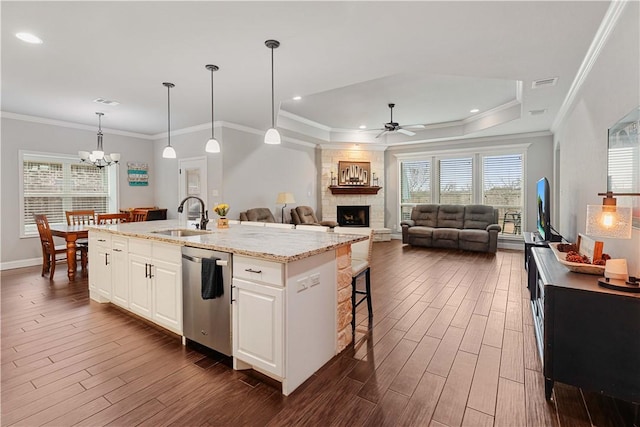 kitchen featuring a stone fireplace, a sink, visible vents, dark wood-style floors, and dishwasher