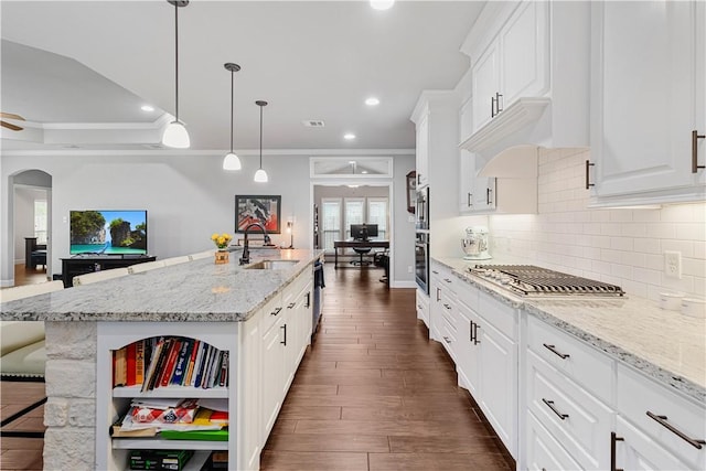 kitchen featuring stainless steel gas cooktop, dark wood-type flooring, a sink, white cabinets, and backsplash