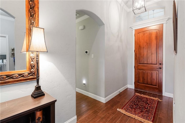 entryway with baseboards, arched walkways, washer / clothes dryer, ornamental molding, and wood finished floors