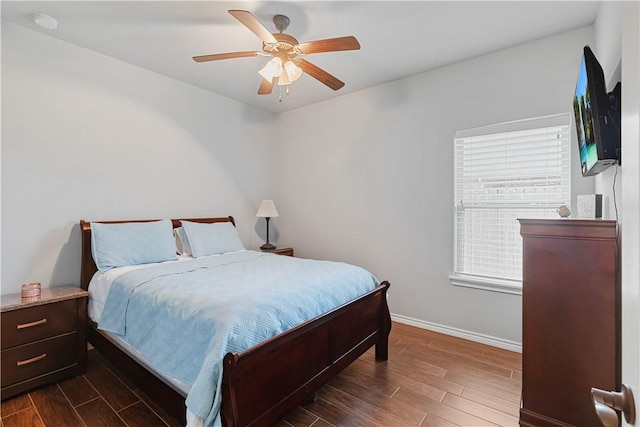 bedroom with dark wood-style floors, ceiling fan, and baseboards