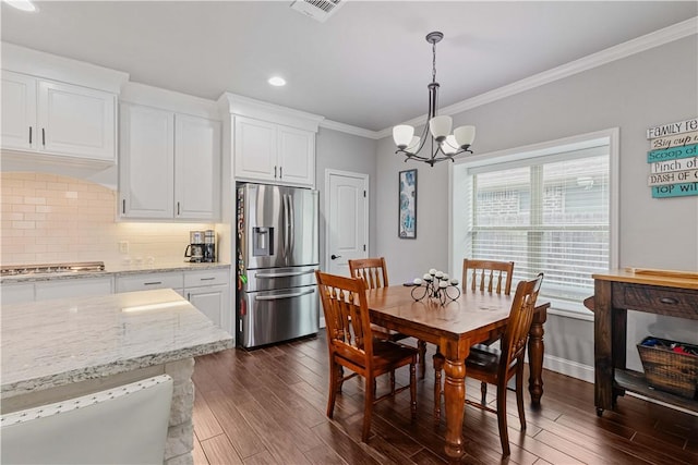 dining area featuring baseboards, visible vents, dark wood finished floors, ornamental molding, and a chandelier