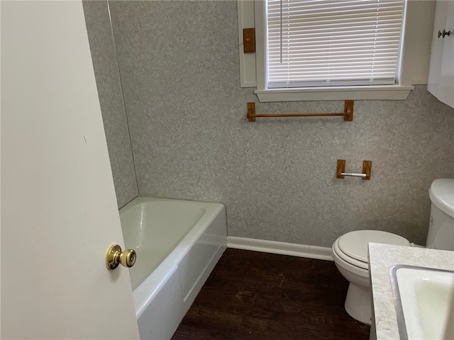 bathroom with a bathing tub, vanity, toilet, and wood-type flooring