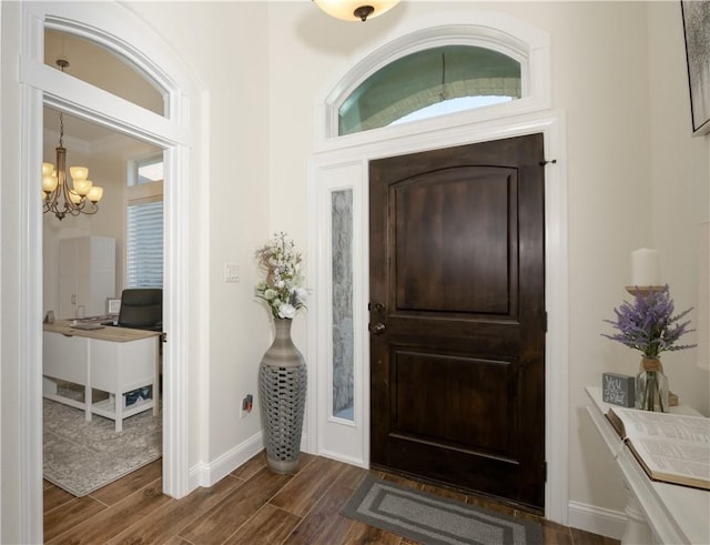 entryway with a healthy amount of sunlight, dark wood-type flooring, and an inviting chandelier