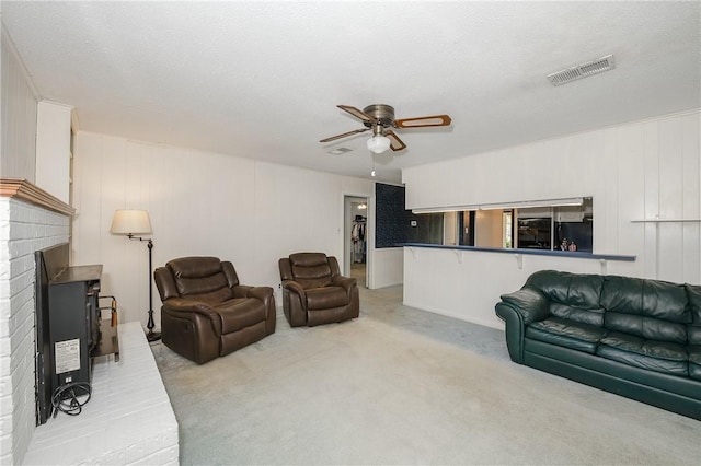 living area featuring a brick fireplace, visible vents, a ceiling fan, and light carpet