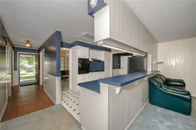 kitchen with white cabinets, oven, dark countertops, a peninsula, and a textured ceiling