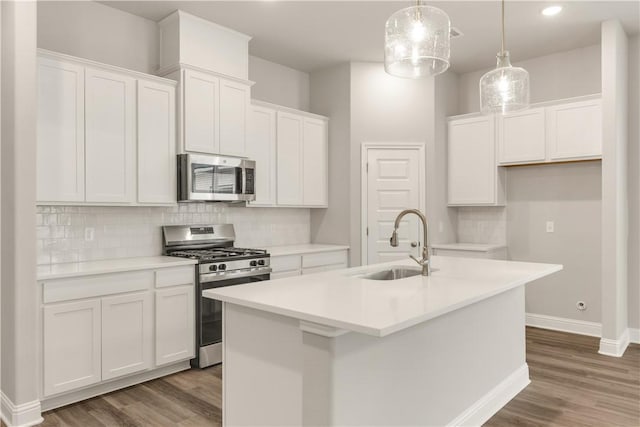 kitchen featuring a sink, stainless steel appliances, a kitchen island with sink, and white cabinets