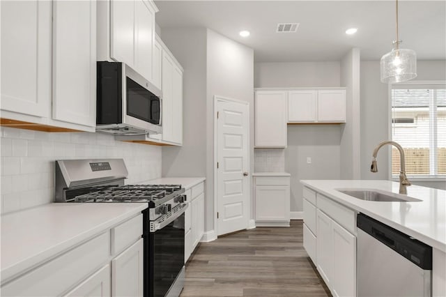 kitchen featuring visible vents, appliances with stainless steel finishes, white cabinetry, and a sink