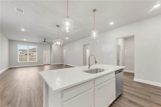 kitchen with visible vents, a sink, light countertops, wood finished floors, and stainless steel dishwasher