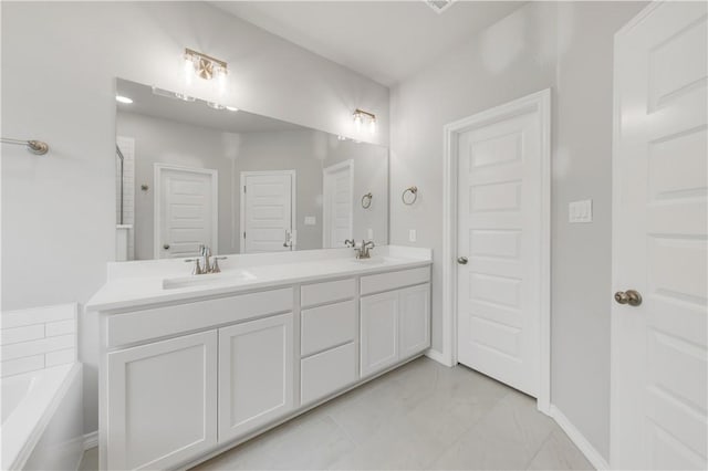 full bath with a sink, baseboards, a garden tub, and double vanity