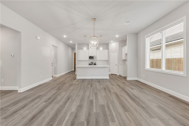 unfurnished living room with visible vents, baseboards, recessed lighting, light wood-style flooring, and a notable chandelier