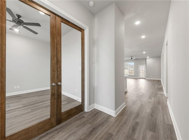 hallway featuring recessed lighting, french doors, baseboards, and wood finished floors